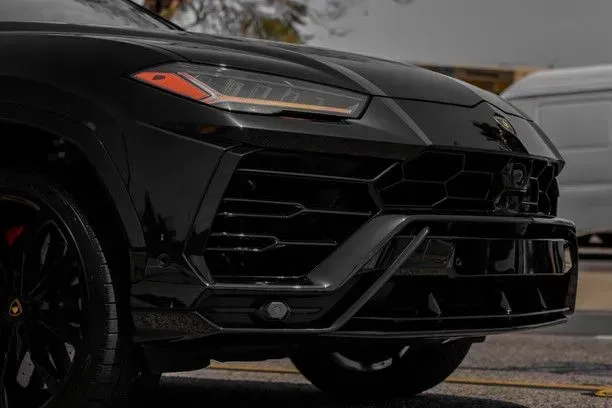 Black Lamborghini Urus SUV, front view, with black grill and headlights.