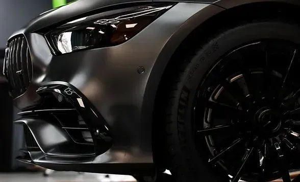 Dark gray sports car front end; black rim and tire visible.