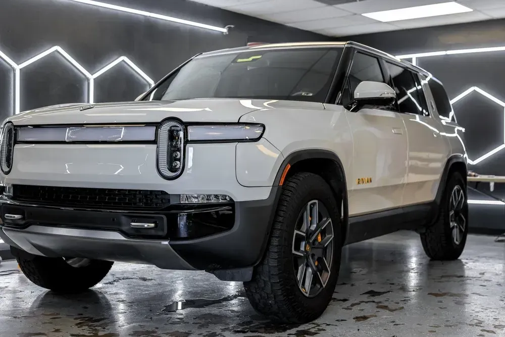 White Rivian SUV in a bright, modern setting.
