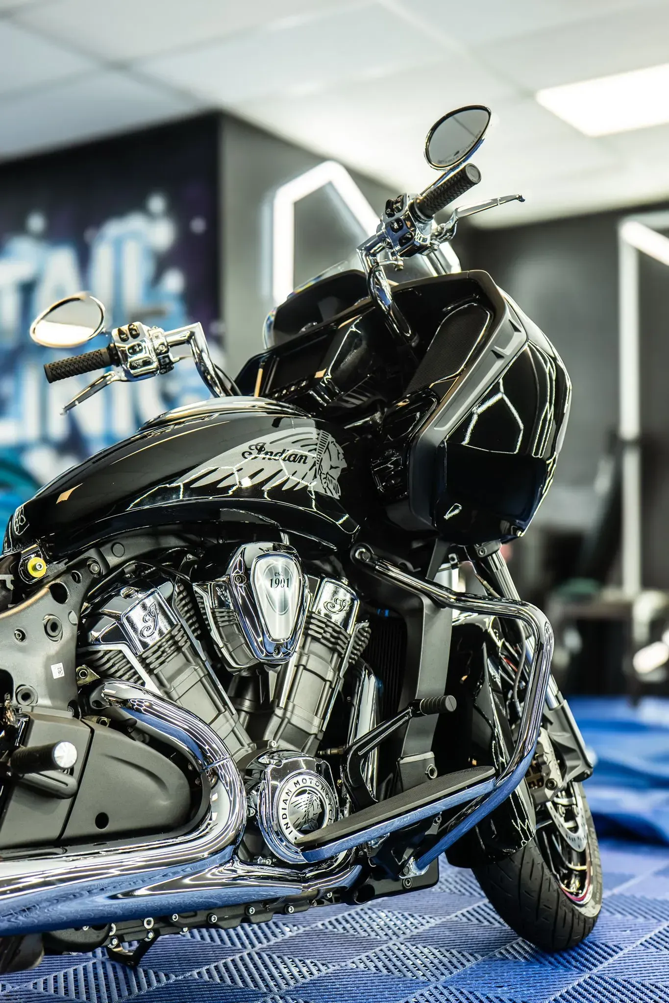 Black and chrome motorcycle inside, bright detailing, in a showroom.