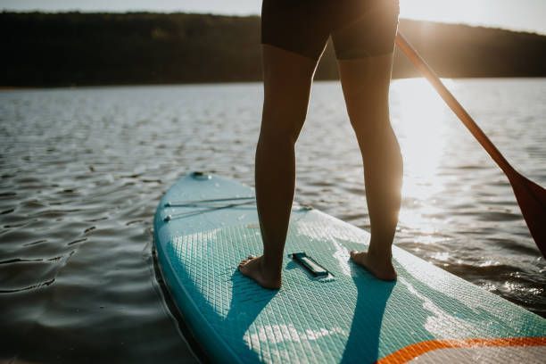 A person is standing on a paddle board in the water.