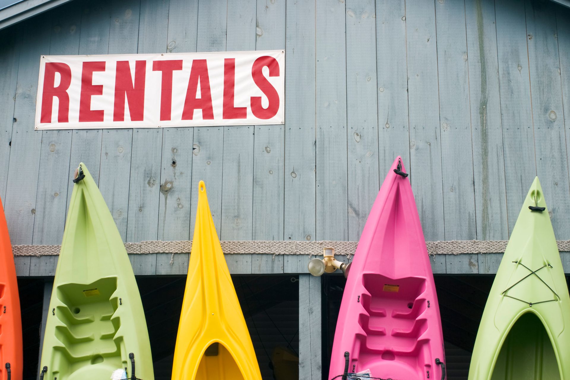 A row of colorful kayaks are lined up under a sign that says rentals