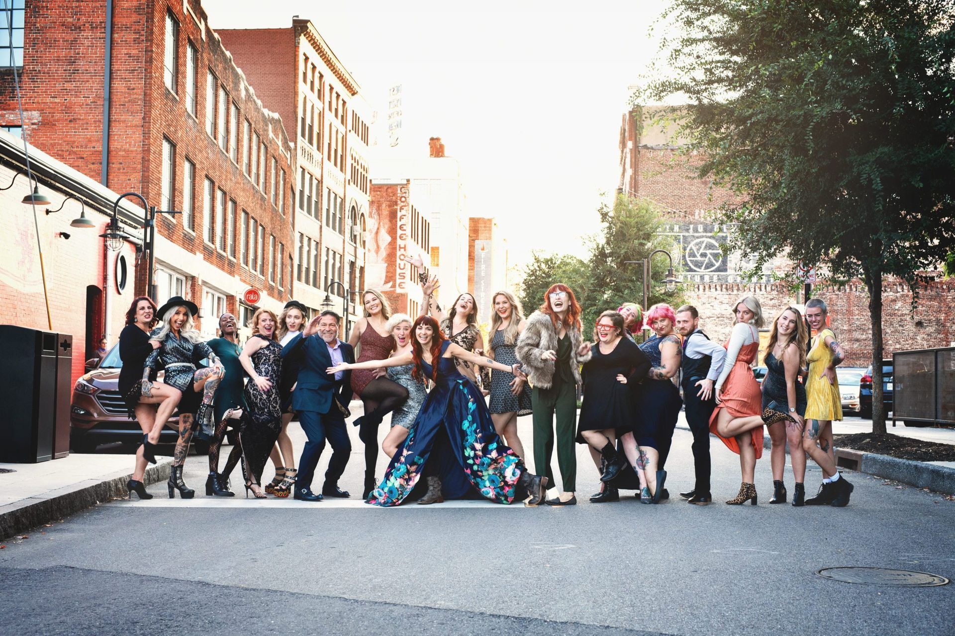 Group of people posing on city street with buildings. Bright lighting.