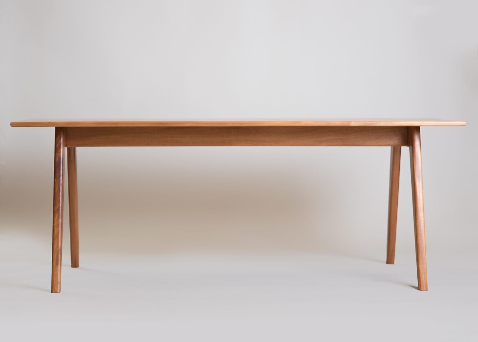 Wooden dining table with tapered legs, against a neutral backdrop.