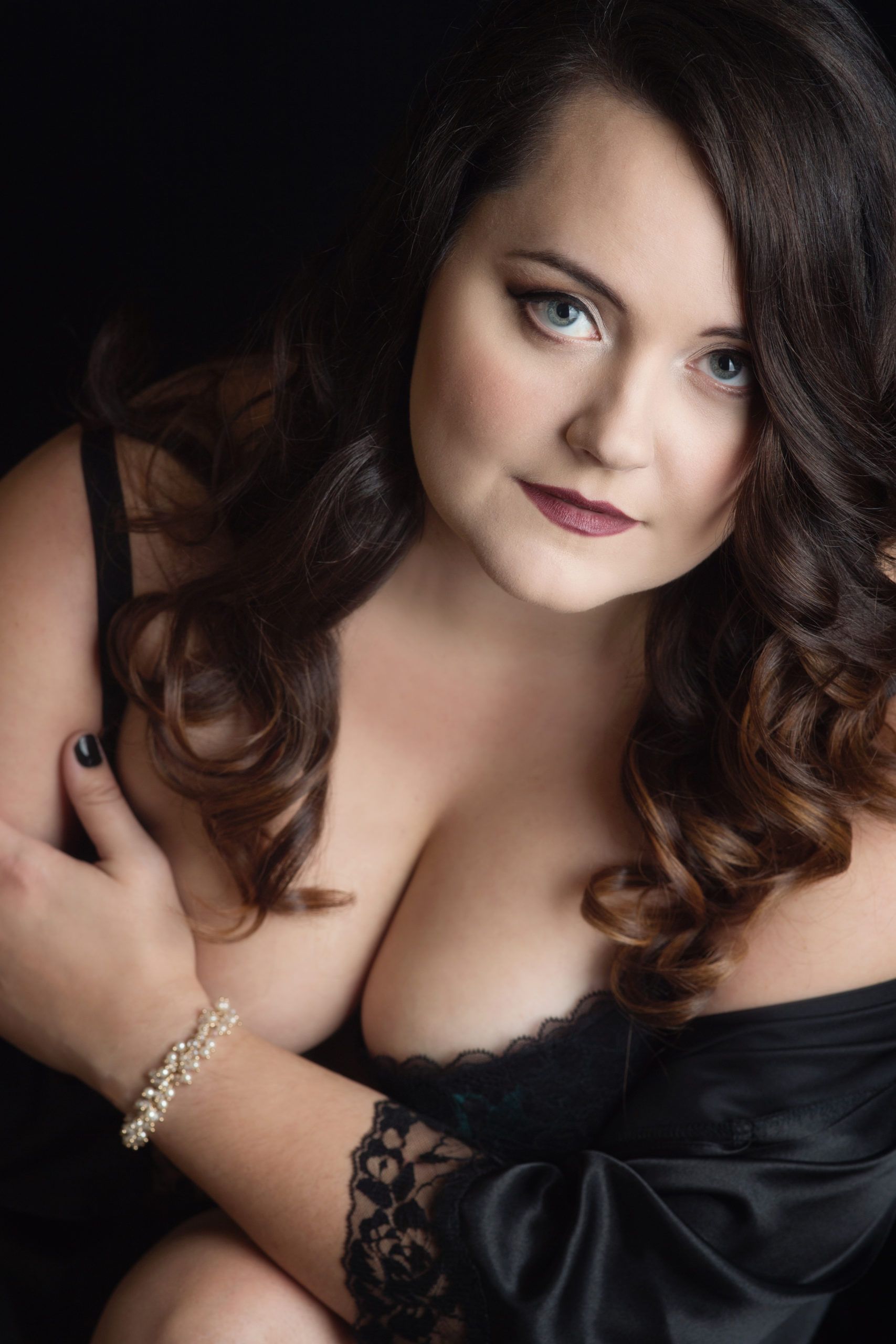 Woman in black lingerie, looking at the camera, dark background.