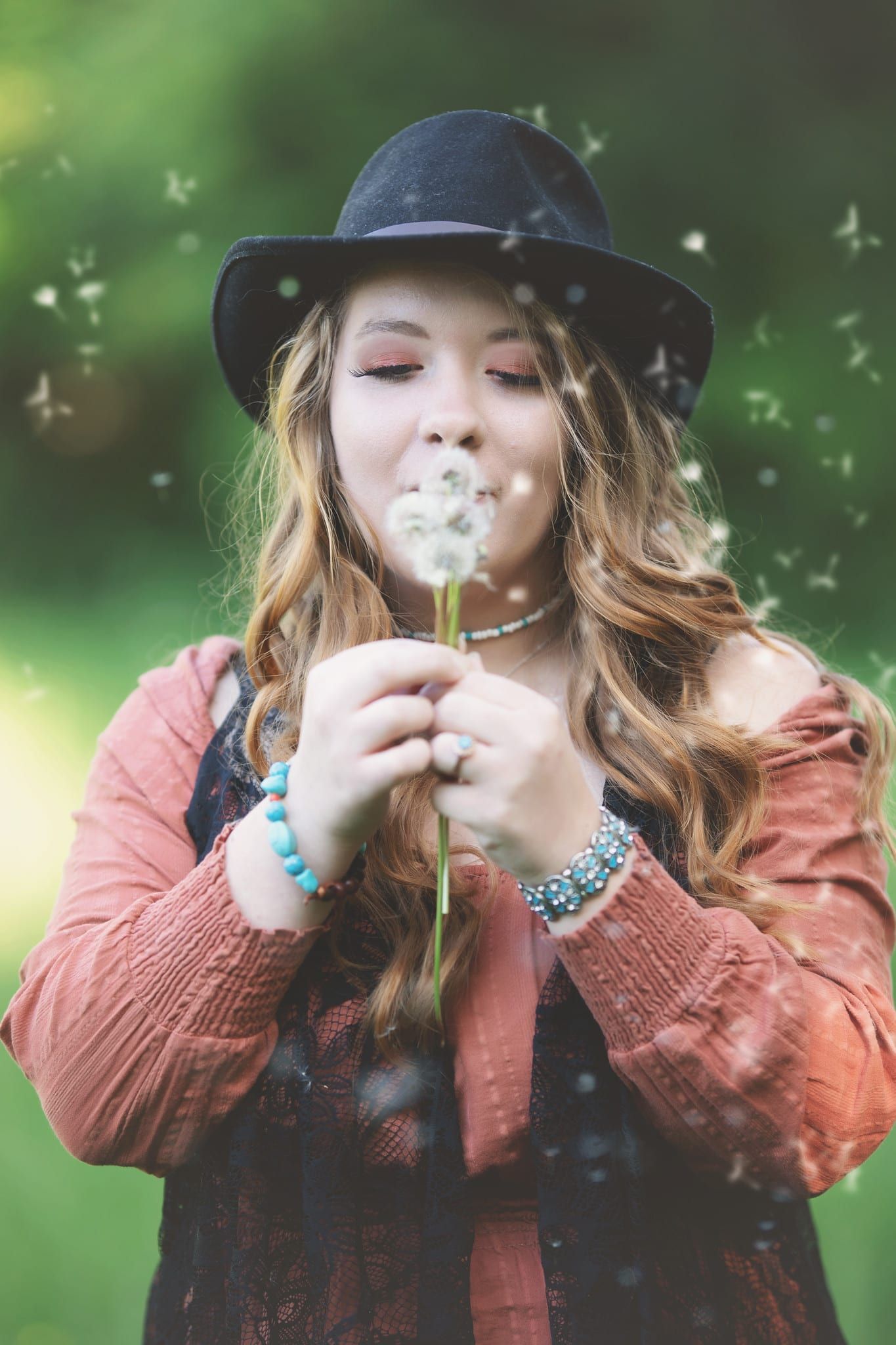 Woman in hat blowing dandelion, outdoors.