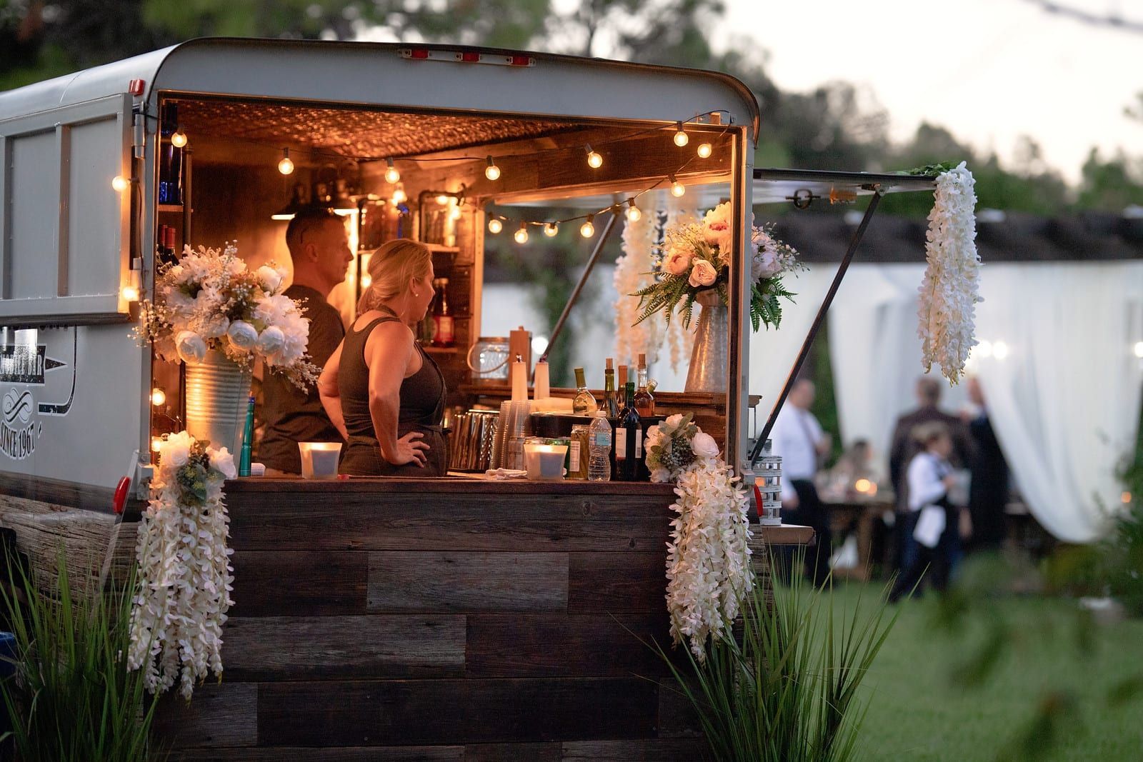 Bar set up in a horse trailer, serving drinks at an outdoor event.