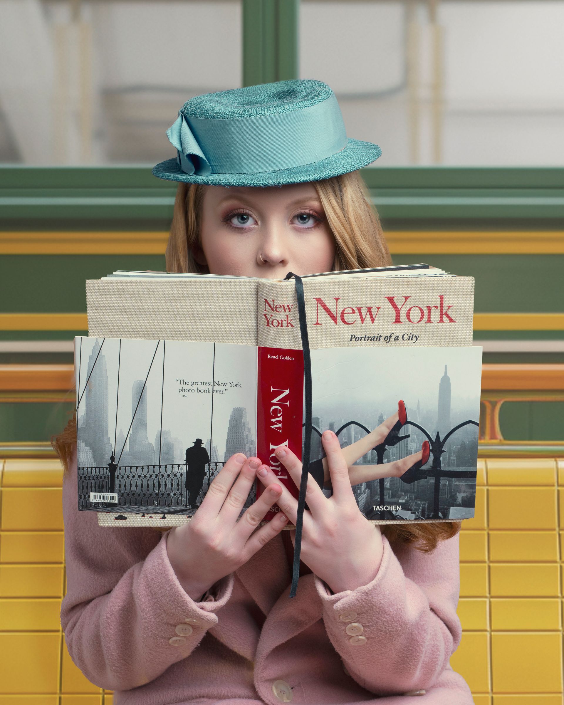 Woman in pink coat and blue hat hides behind a 