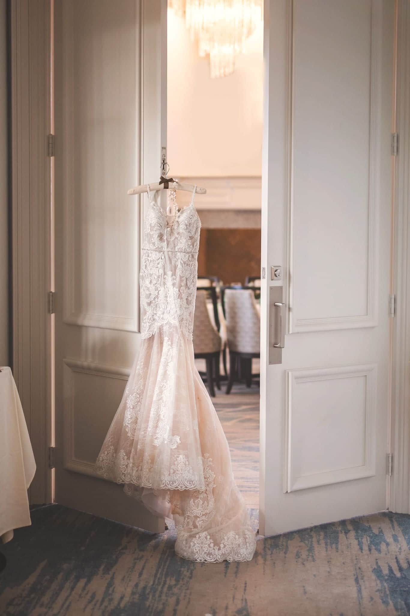 Wedding dress hanging in doorway, soft lighting.