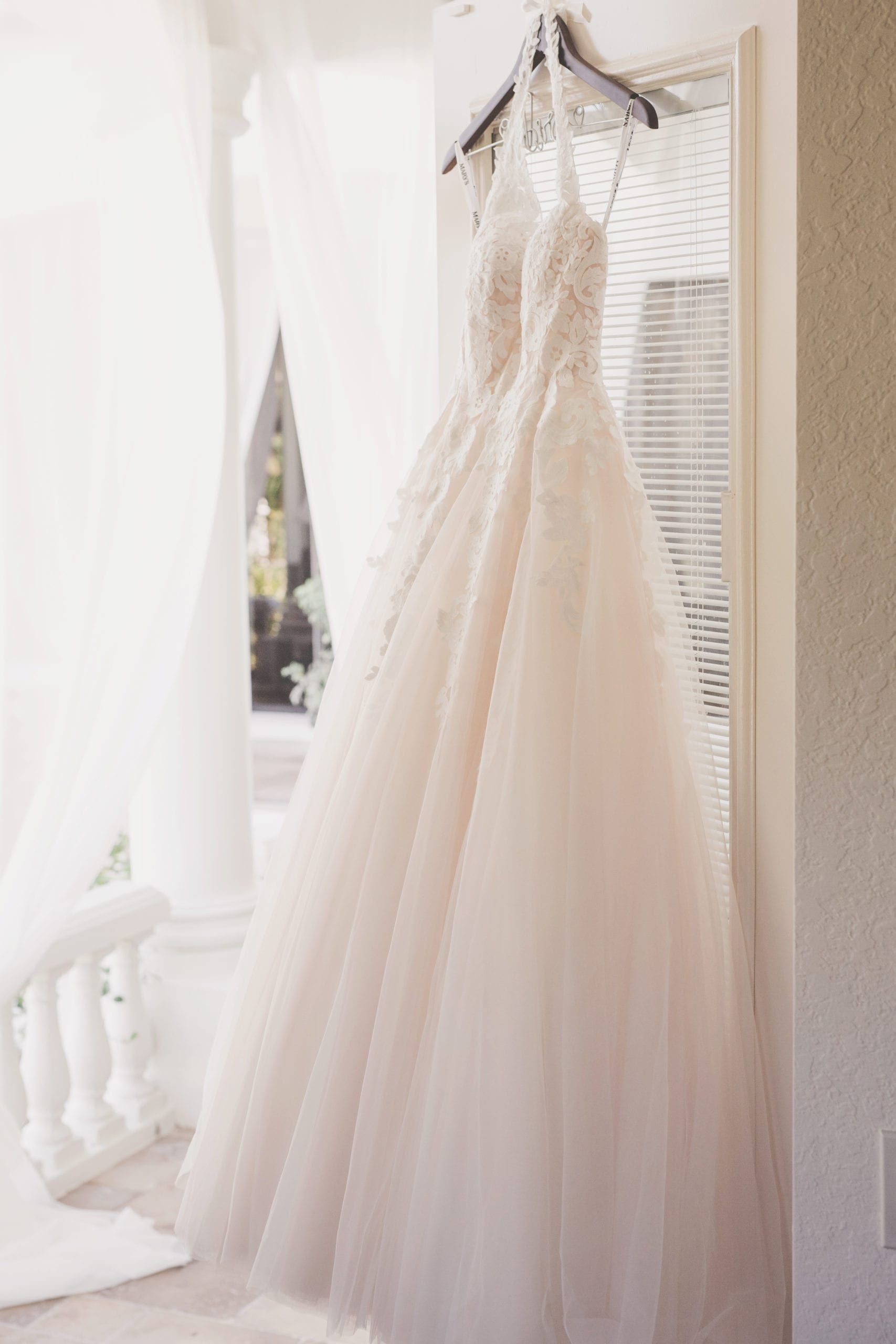 Wedding dress hanging in doorway, ivory lace bodice, tulle skirt.