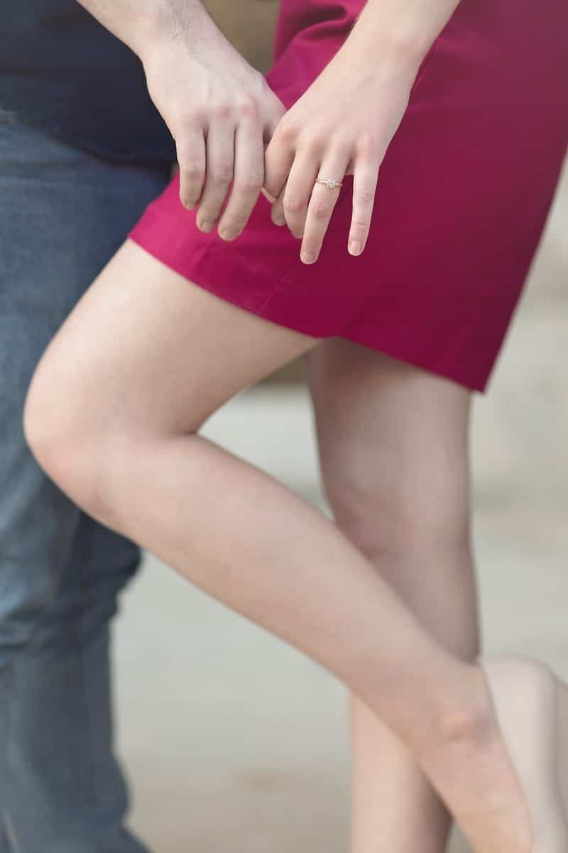 Couple holding hands, woman in a red dress, leg raised, man in jeans.