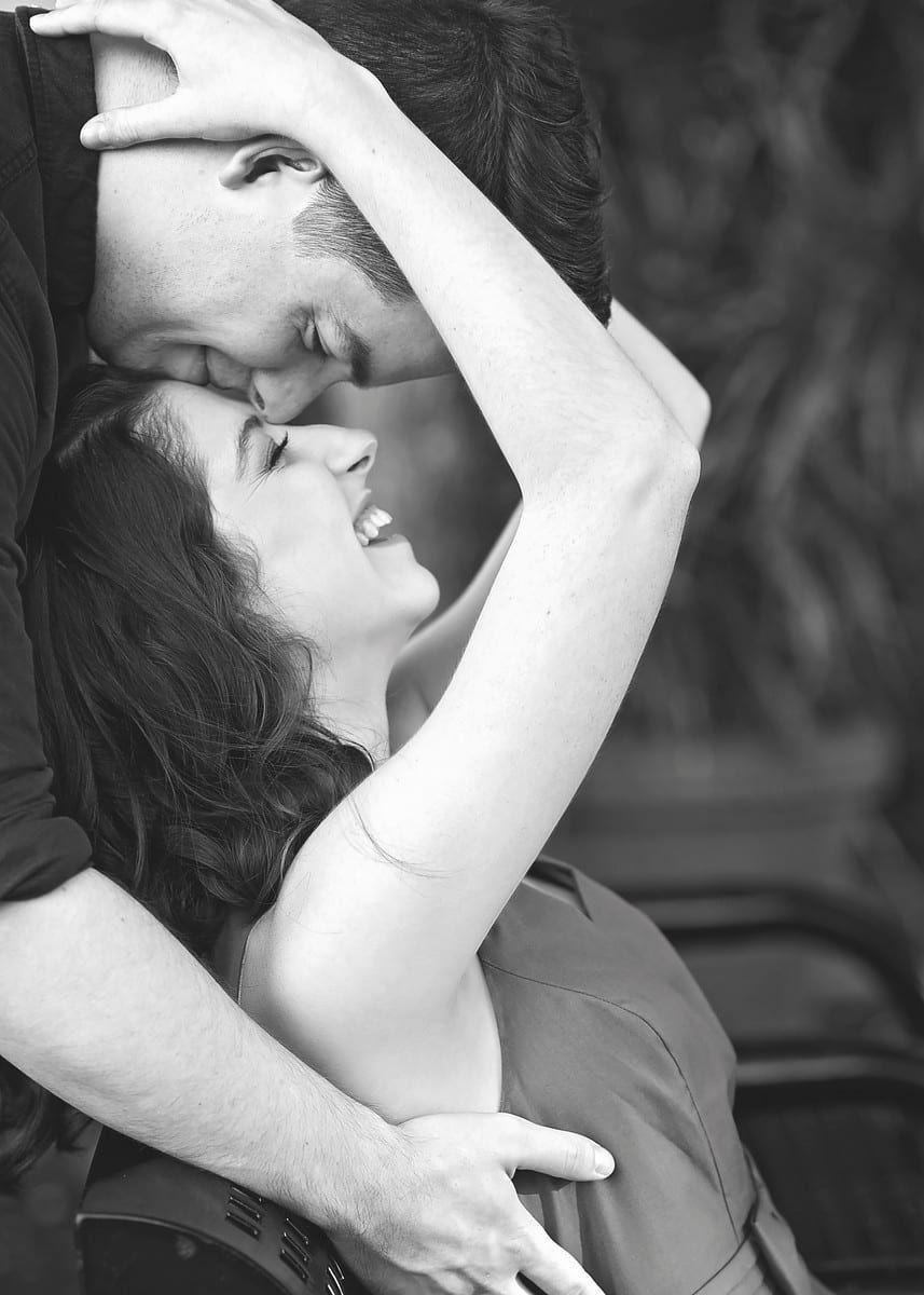 Man and woman embracing, laughing; outdoors, black and white.