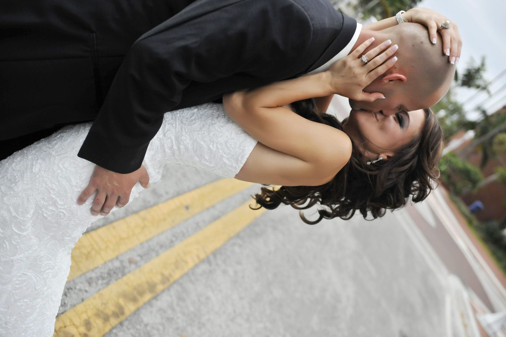 Bride and groom kissing; woman in white dress leans back as man in suit leans to kiss her.