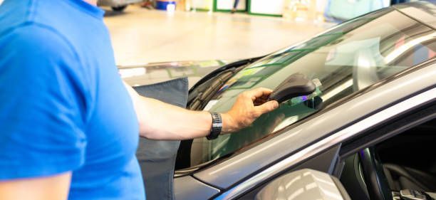 Mechanic inspecting auto glass for windshield repair or replacement.