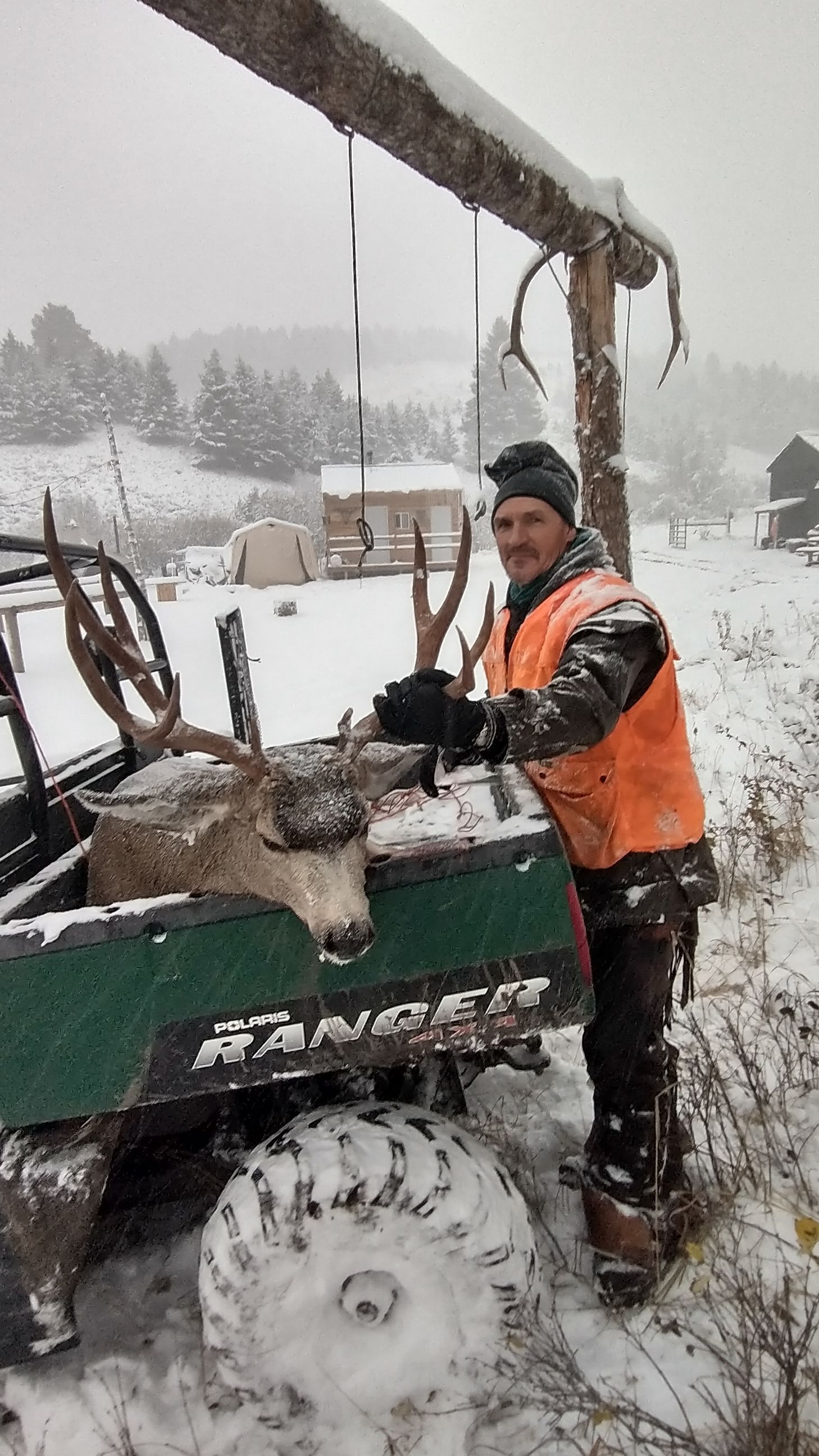A man is standing next to a deer in the snow.