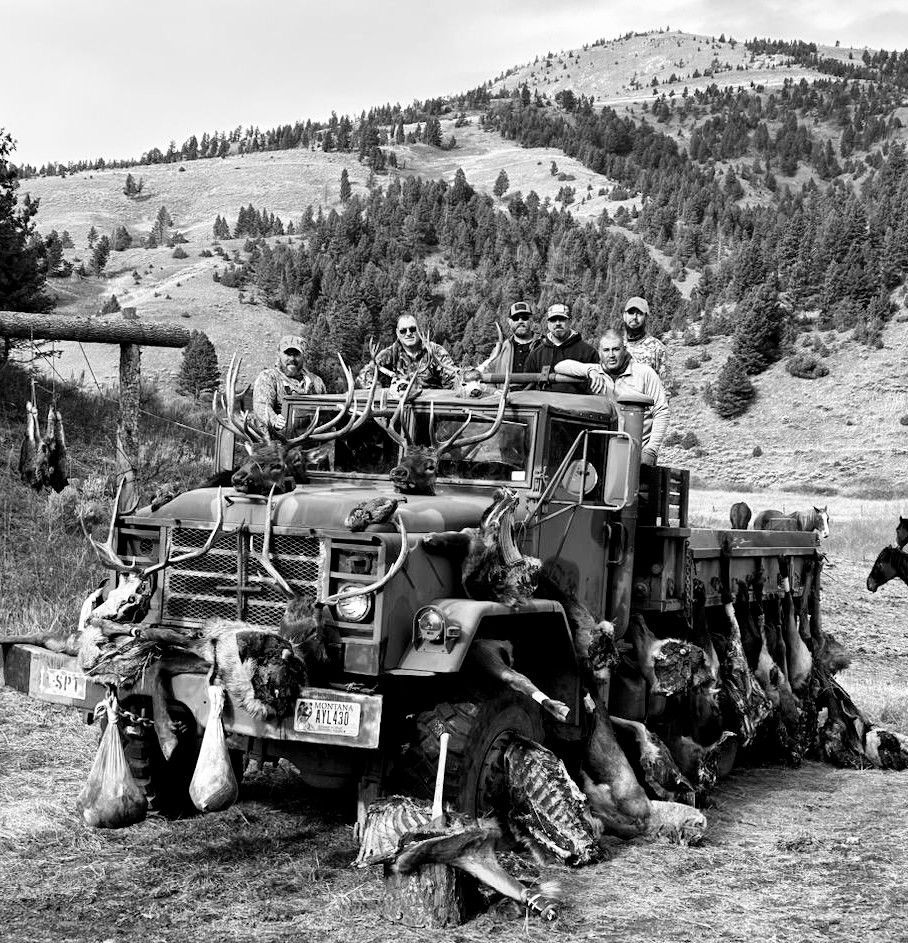 A black and white photo of a group of people sitting on top of a truck.