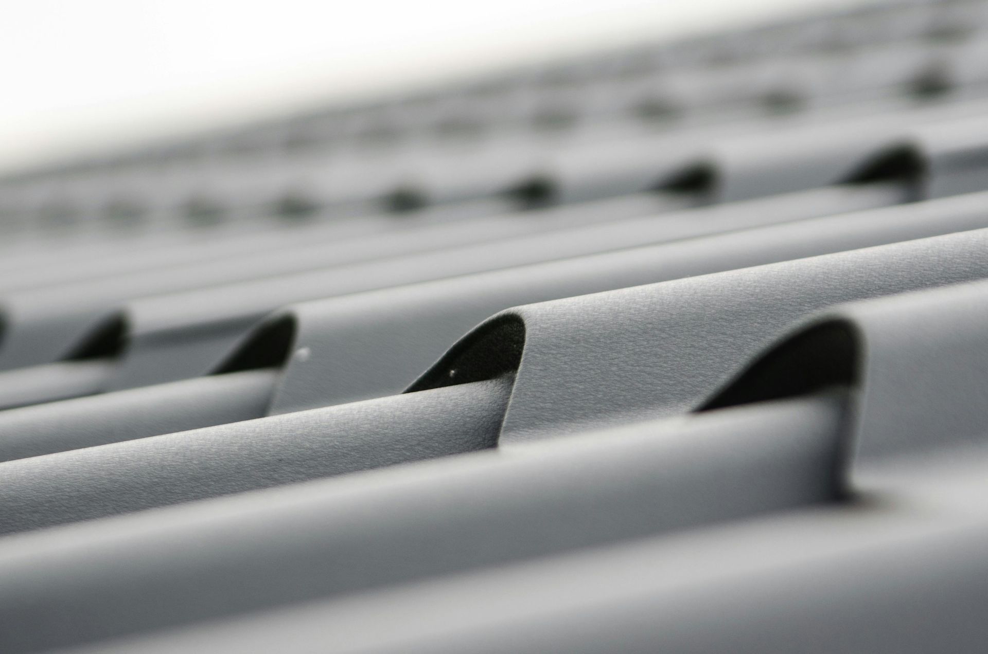 Rows of gray metal roofing panels with repeating ridges in soft focus