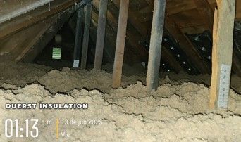 Attic with loose-fill insulation, wooden beams, pipes.