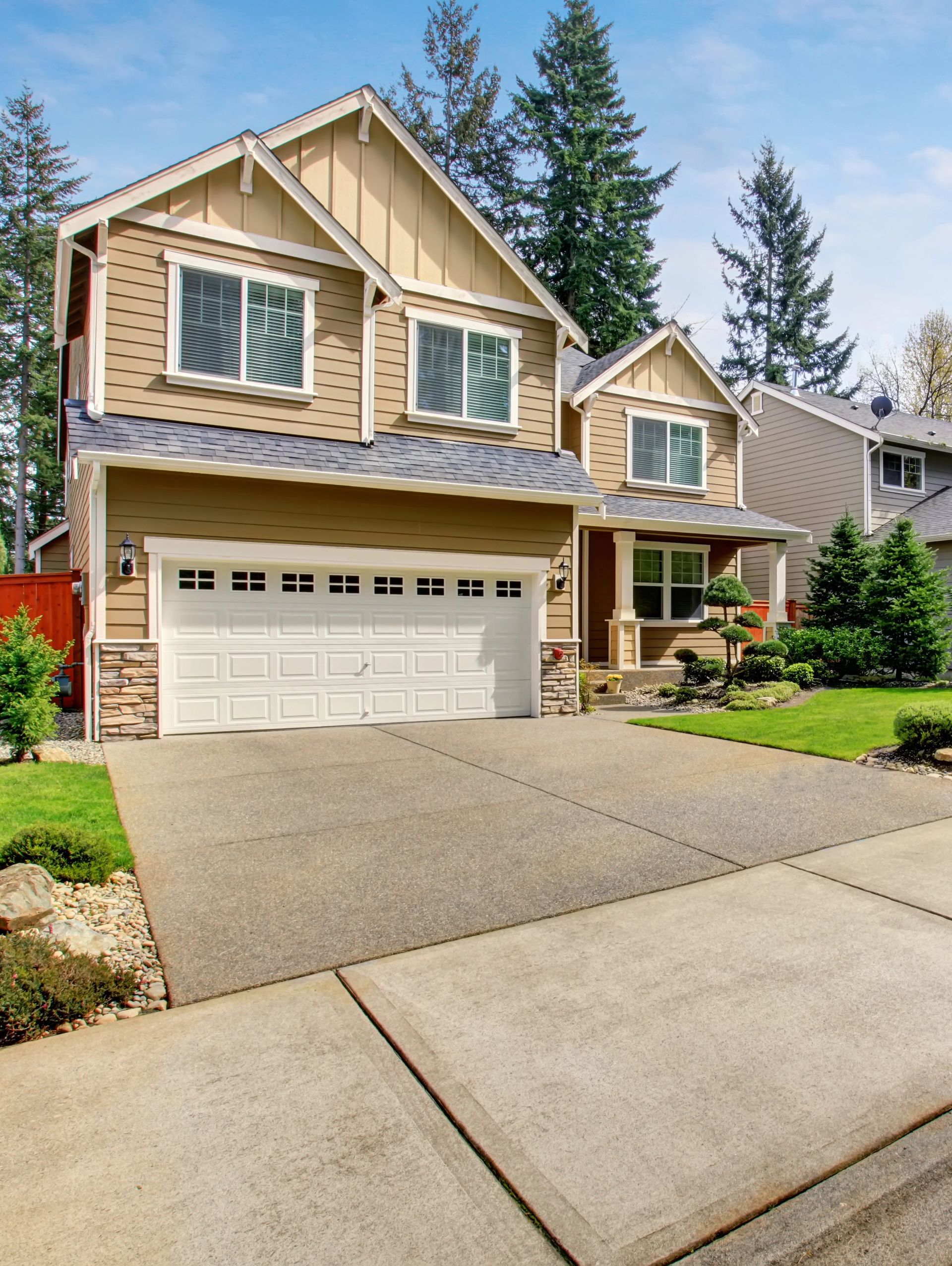 Two-story beige house with a driveway and garage, set in a neighborhood.