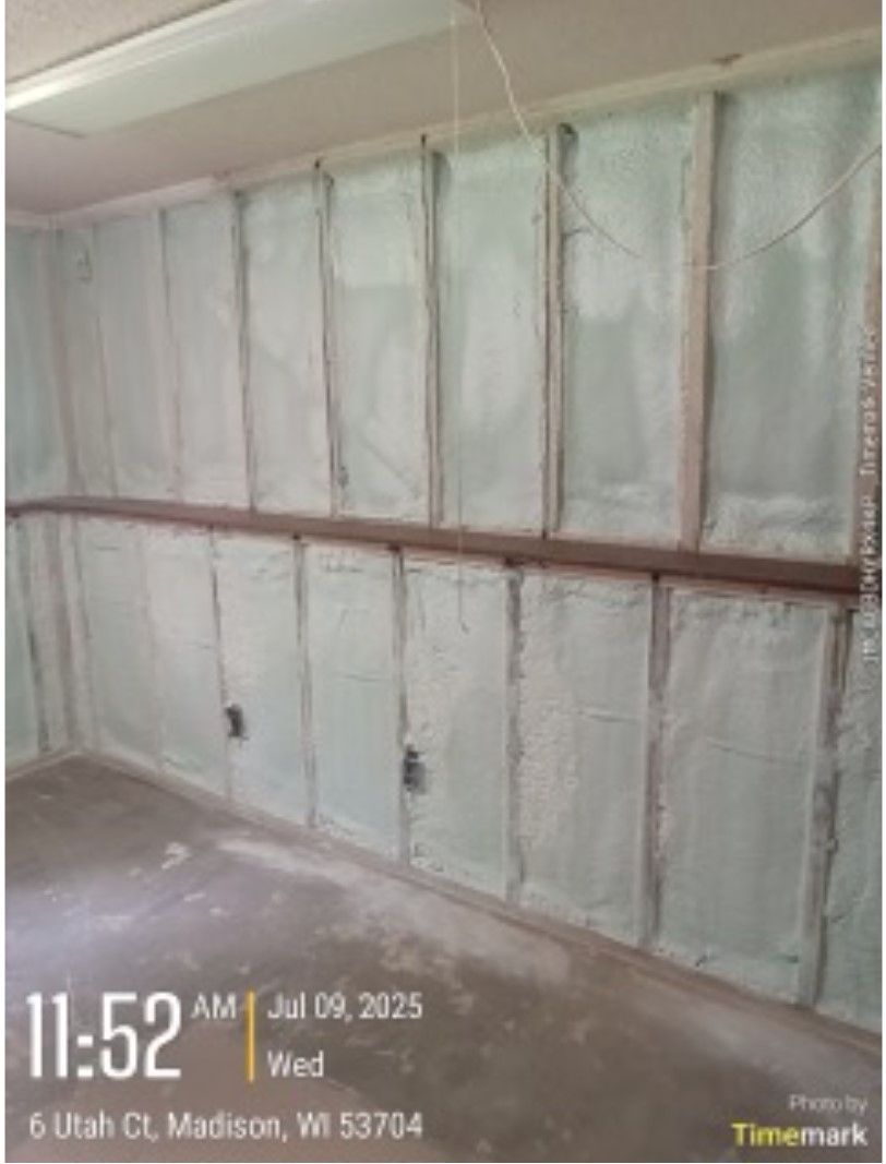 Garage wall with insulation, studs, and electrical outlets.