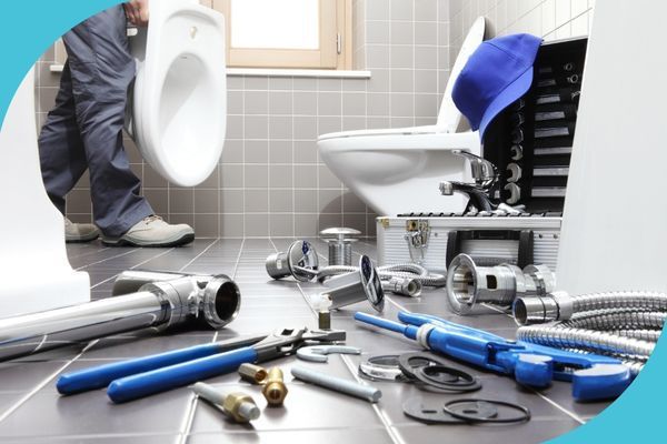 Plumber installing a toilet, tools and parts scattered on the bathroom floor.