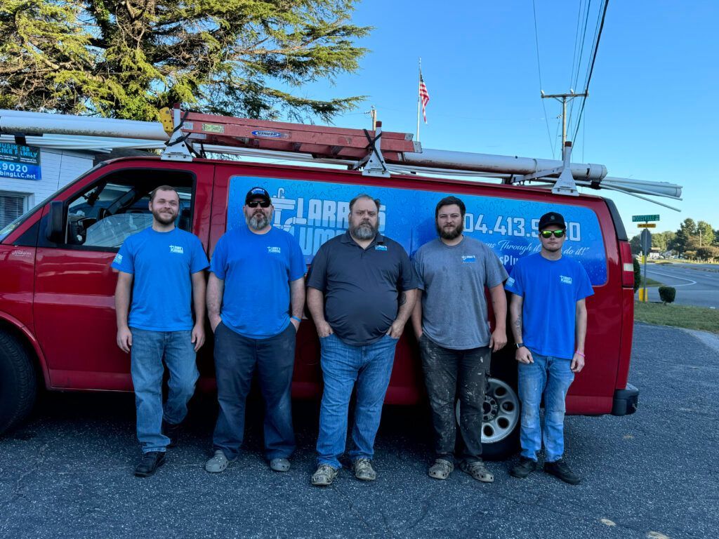 Five men standing in front of a red van. They're wearing blue shirts, and the van has a business logo on the side.