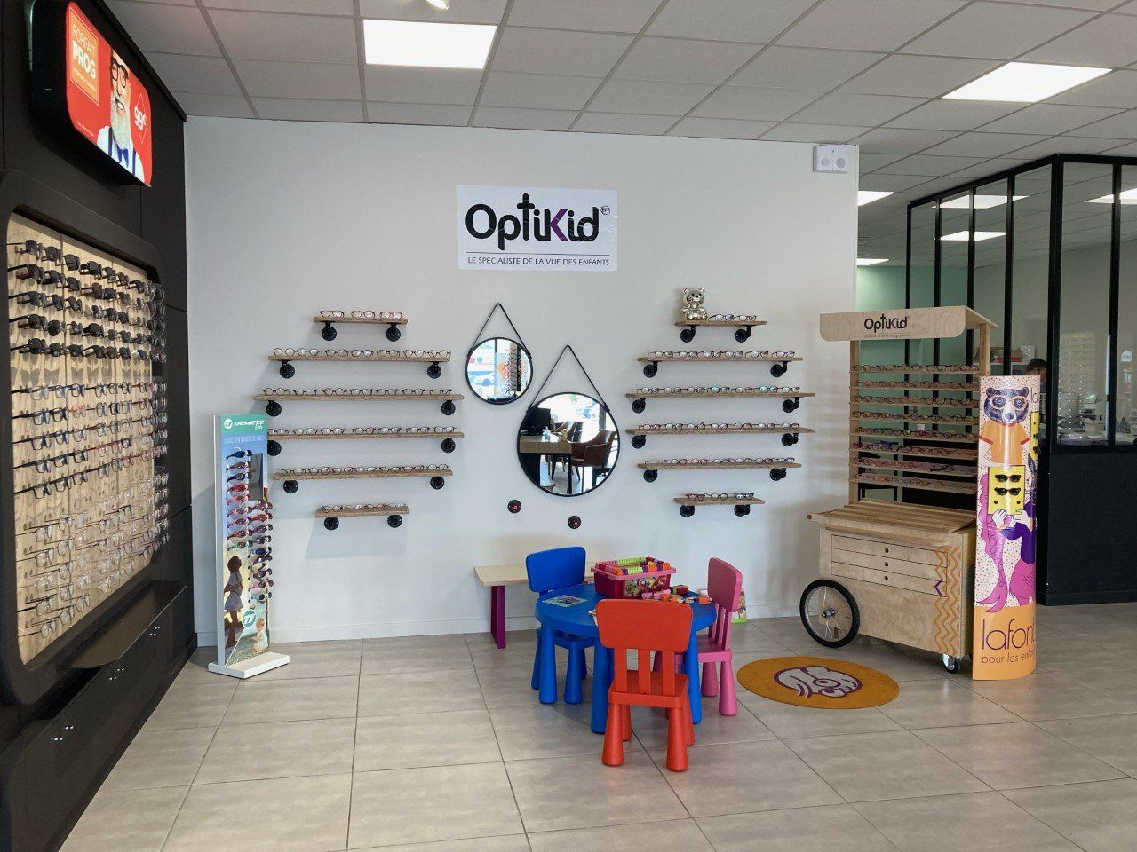 Intérieur du magasin de lunettes Optikid avec tables pour enfants et présentoirs à lunettes.