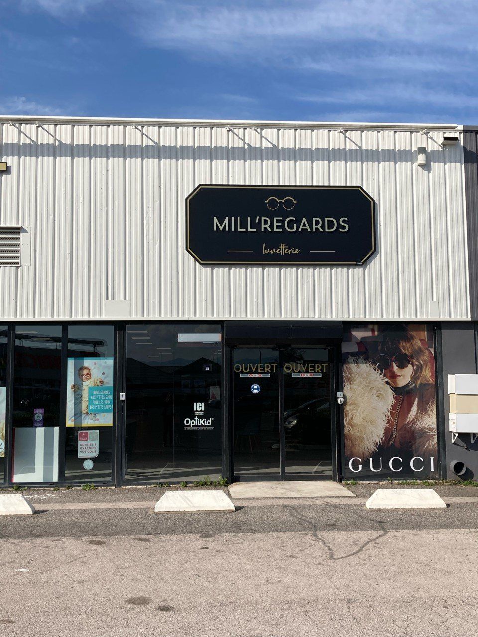 Façade du magasin Mill'Regards avec enseigne noire, portes vitrées et publicité Gucci.