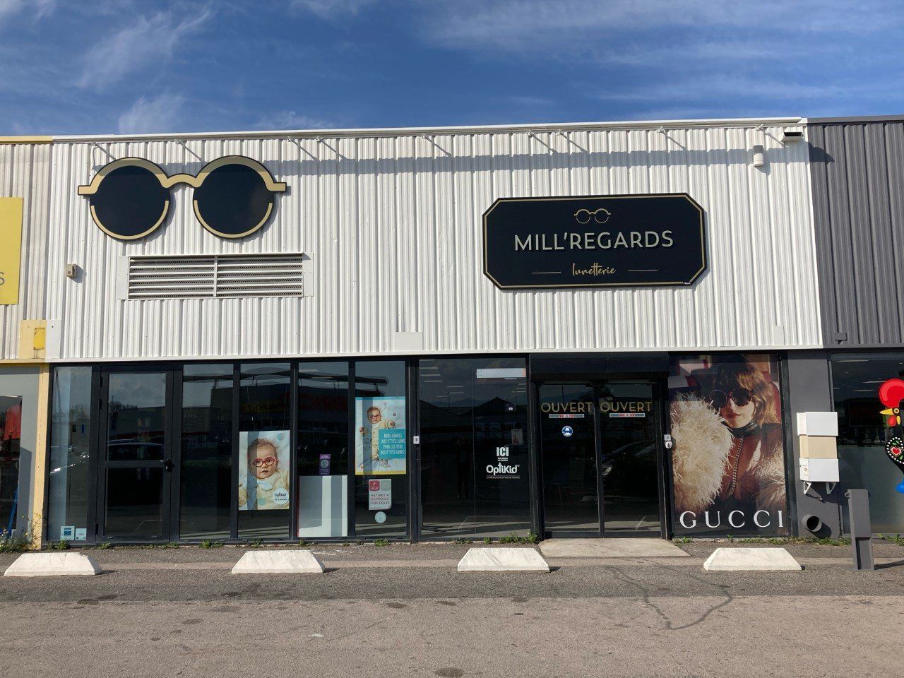 Façade du magasin d'optique « Mille Regards » ornée de grandes lunettes.
