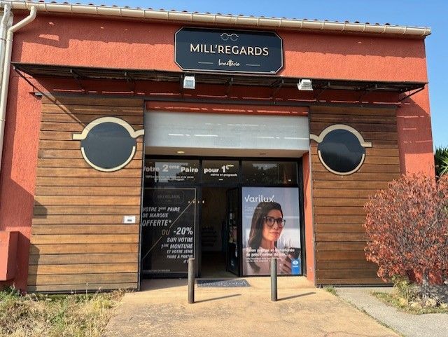Extérieur d'un magasin d'optique appelé Mill'Regards, avec une façade en bois.