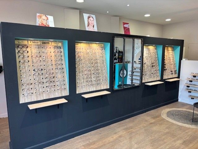 Intérieur d'un magasin d'optique avec des présentoirs muraux bleu foncé. Lunettes exposées,