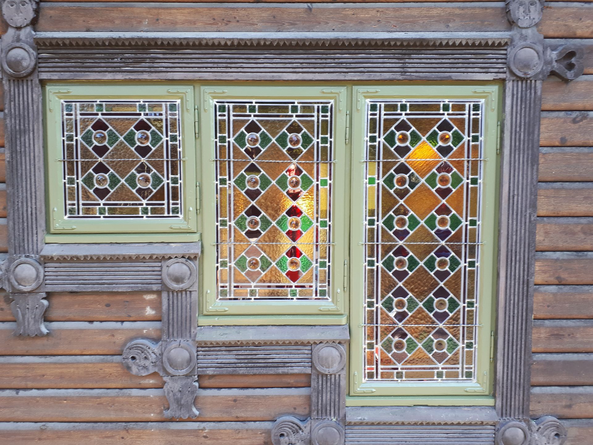 A window with stained glass on a wooden wall