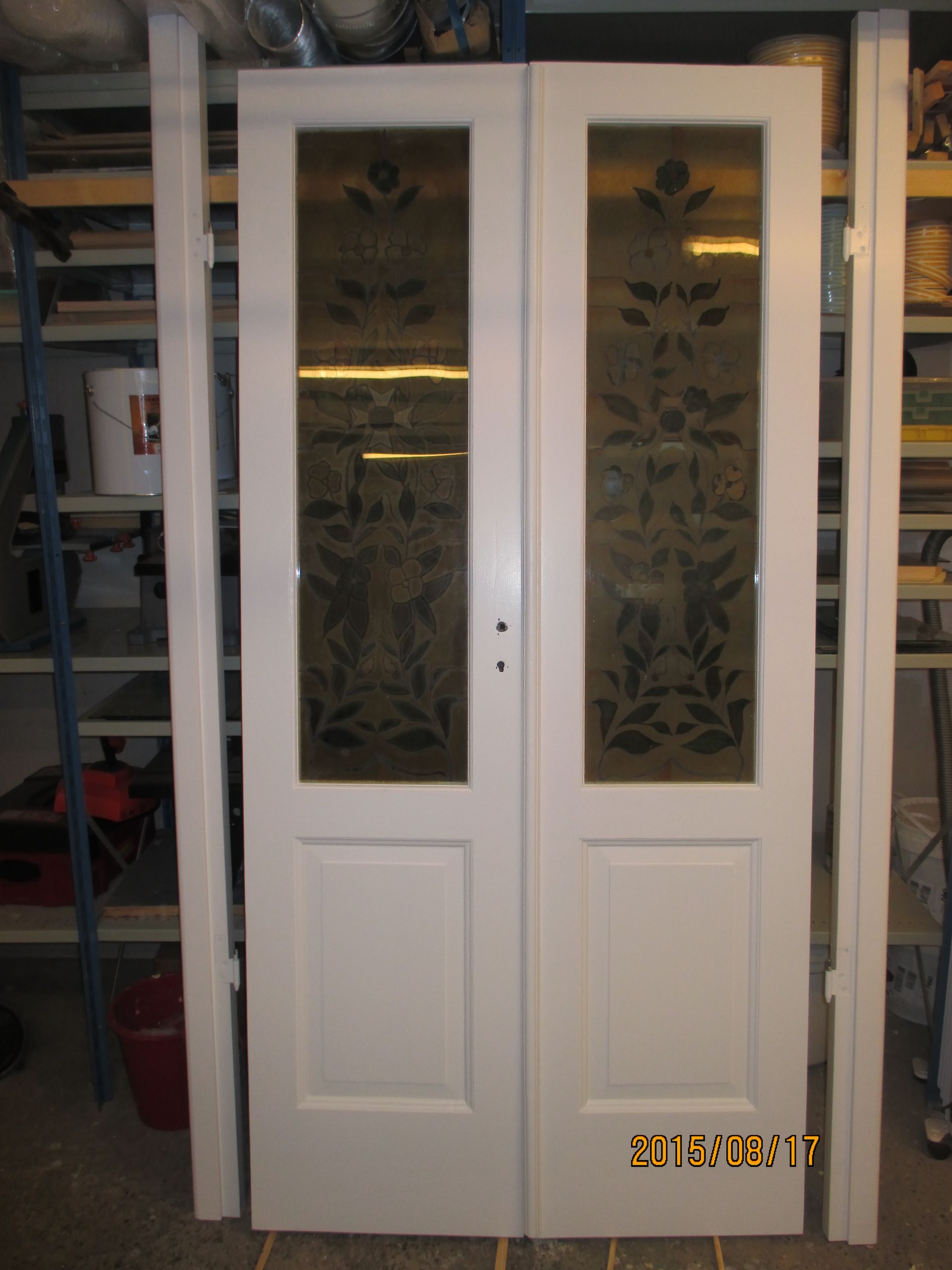 A pair of white doors with a floral design on the glass