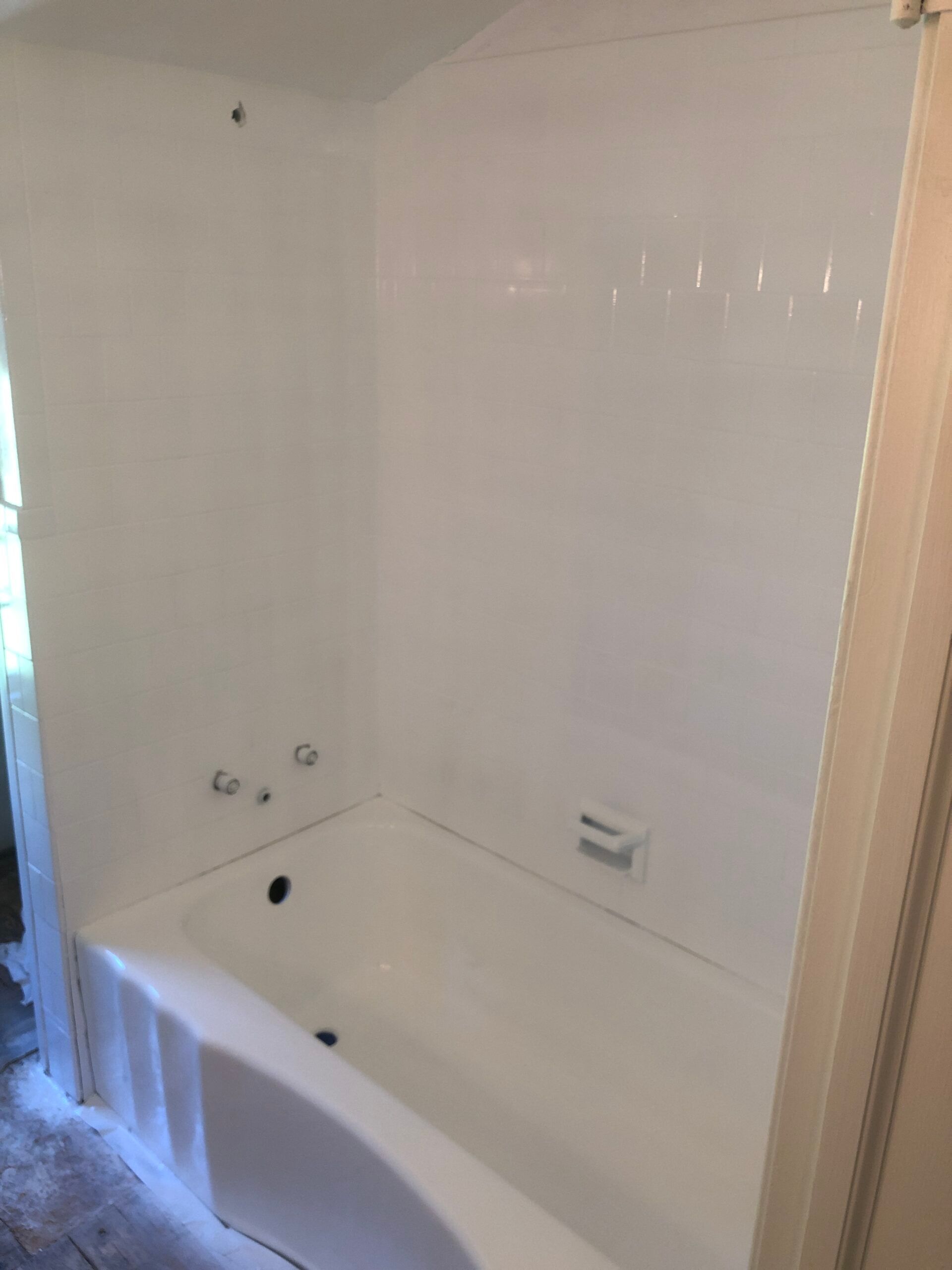 White bathroom with a tub and shower, soap dish, and chrome fixtures.
