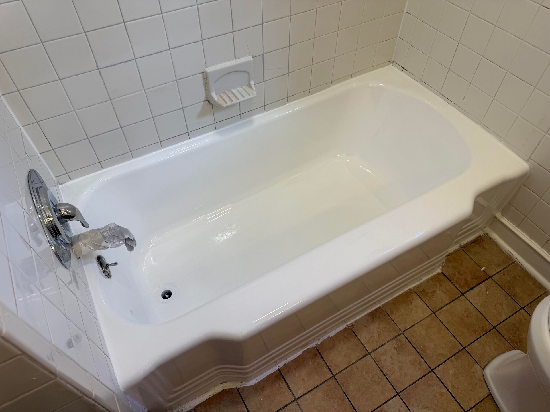 White bathtub with chrome faucet and showerhead in a tiled bathroom
