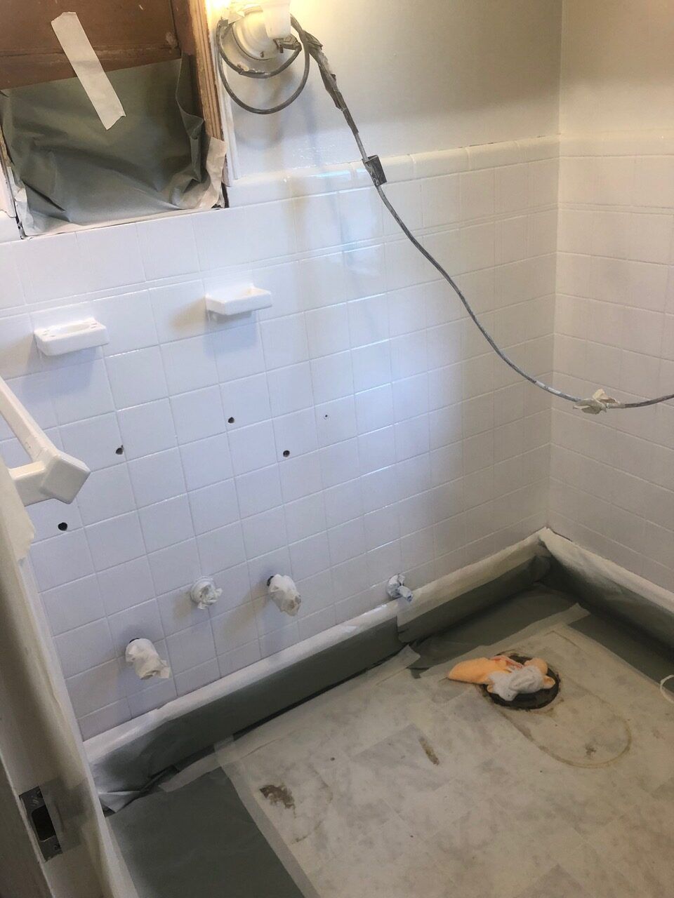 White-painted basement wall with plumbing fixtures, partially finished. A gray floor leads to the corner.