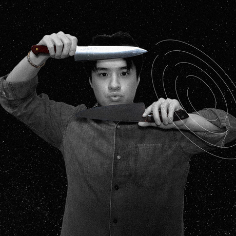 Man juggling three knives in a dark space, making a surprised face.