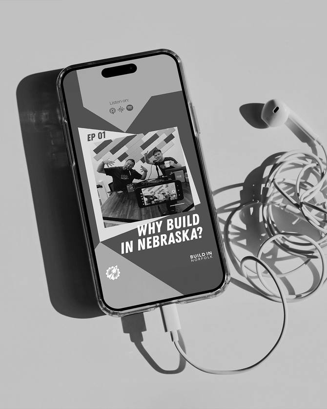 Three people smiling at a booth. Woman in scrubs and man in beanie stand front; man in cap stands behind.