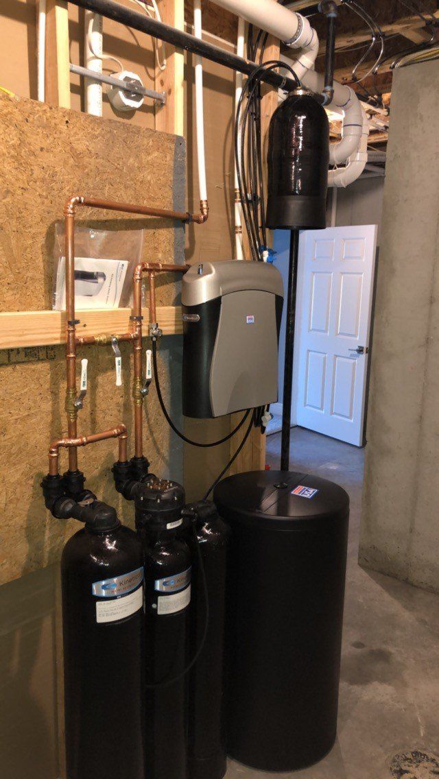A basement with a lot of pipes and a water softener.