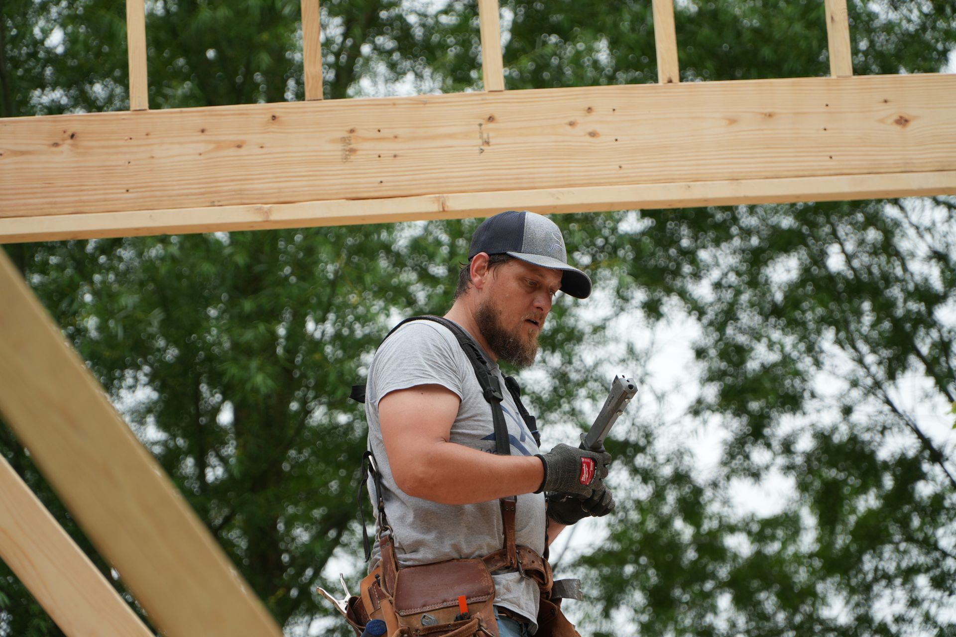 A man is working on a wooden structure while holding a hammer.