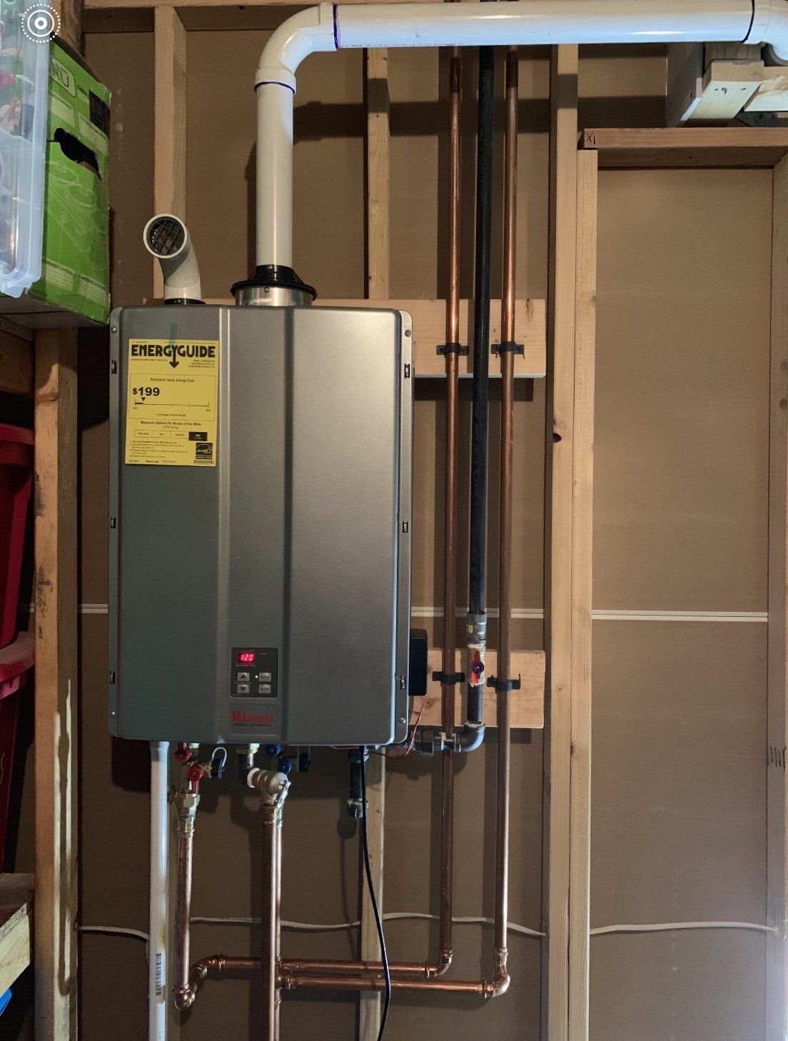 A water heater is mounted to a wall next to copper pipes.