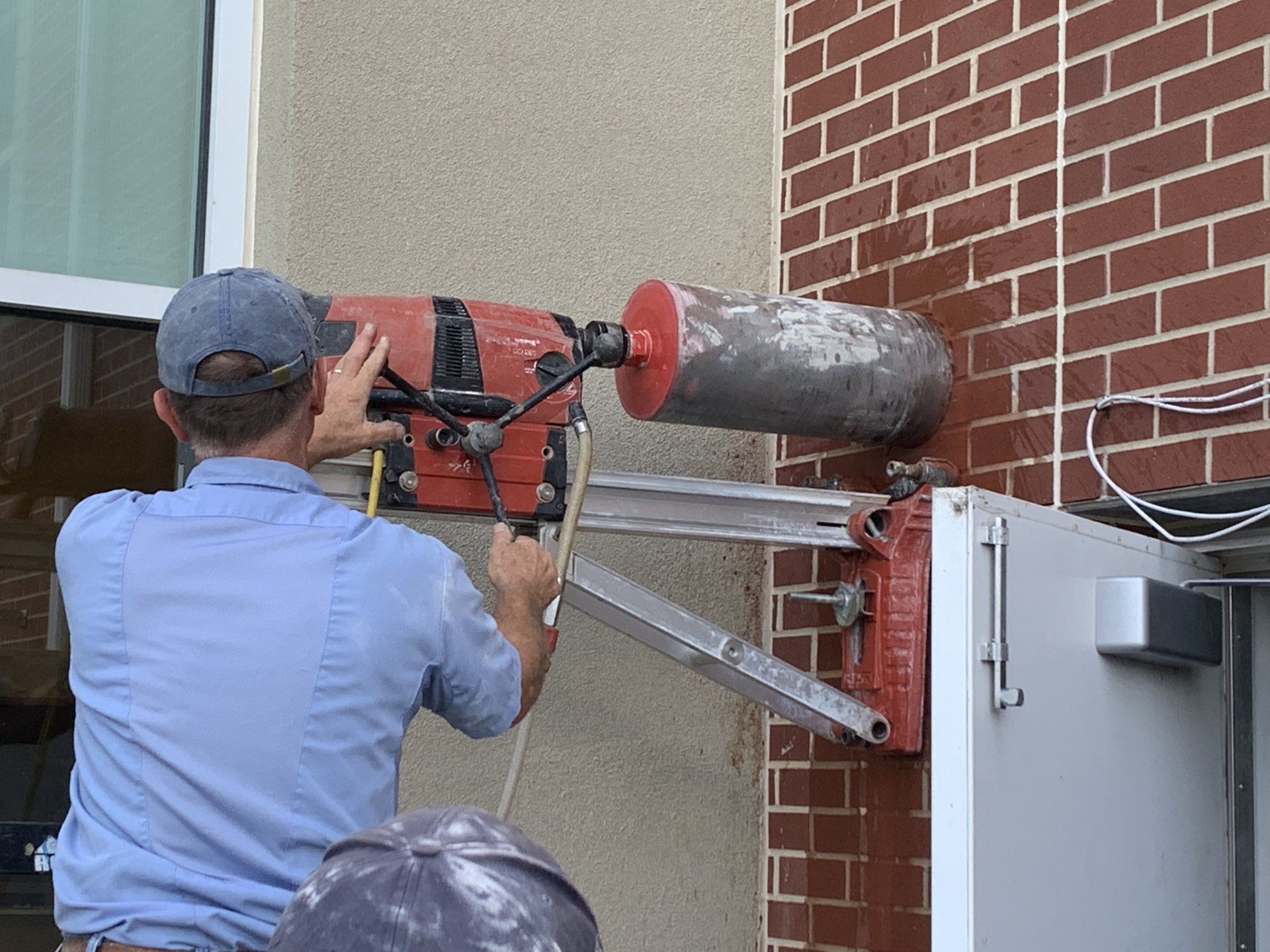A man is using a machine to drill a hole in a brick wall.