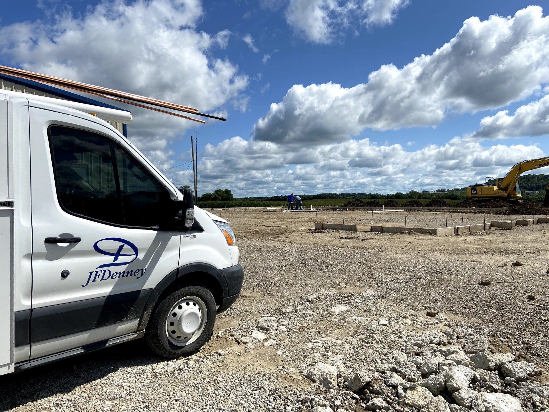A white van is parked in front of a construction site.