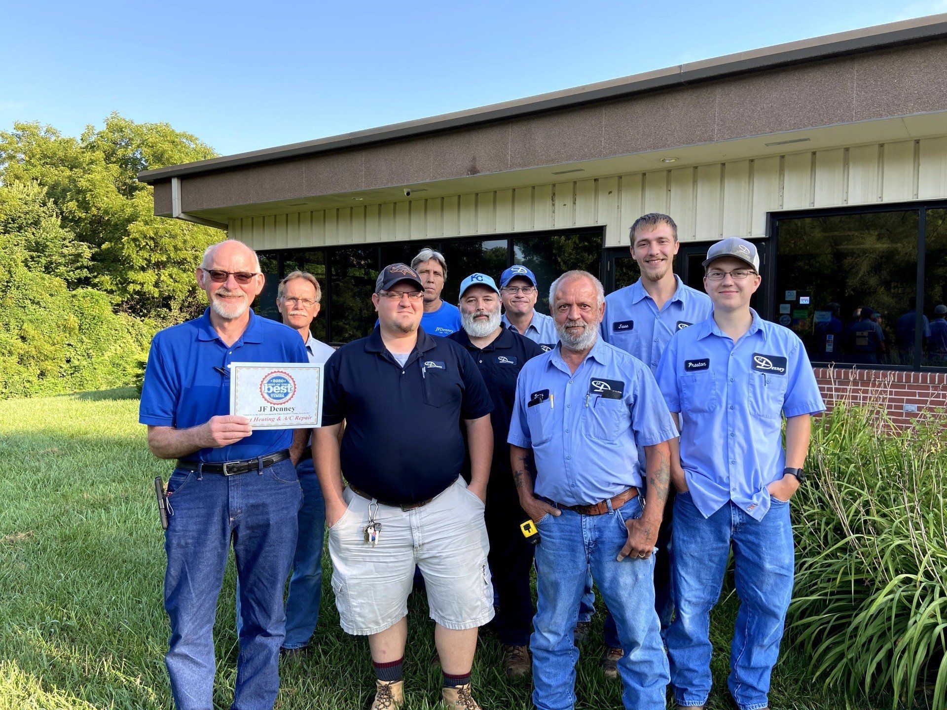 A group of men are posing for a picture in front of a building.