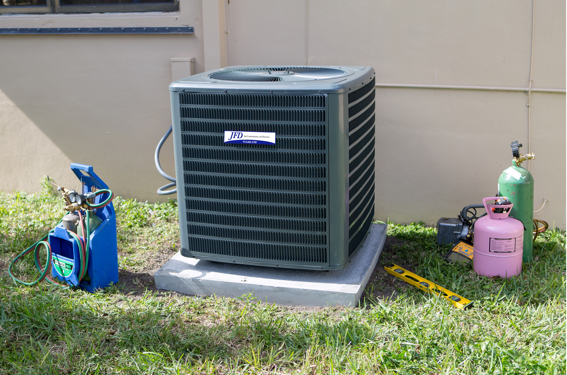 An air conditioner is sitting on a concrete block in the grass.