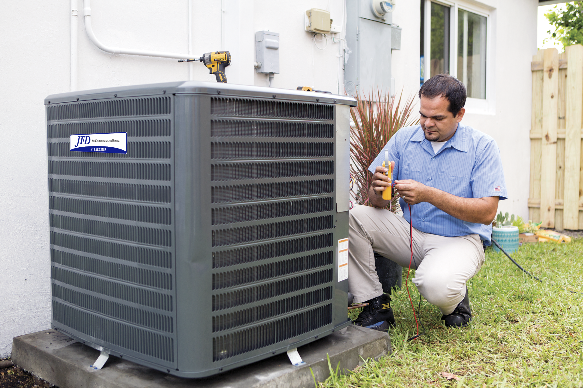 A man is working on an air conditioner outside of a house.