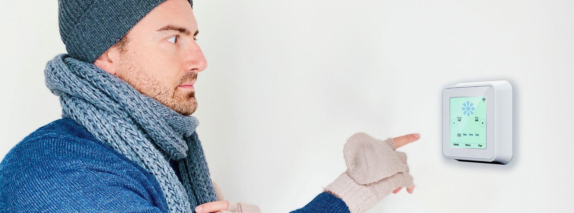 Picture of a man bundled up at a thermostat