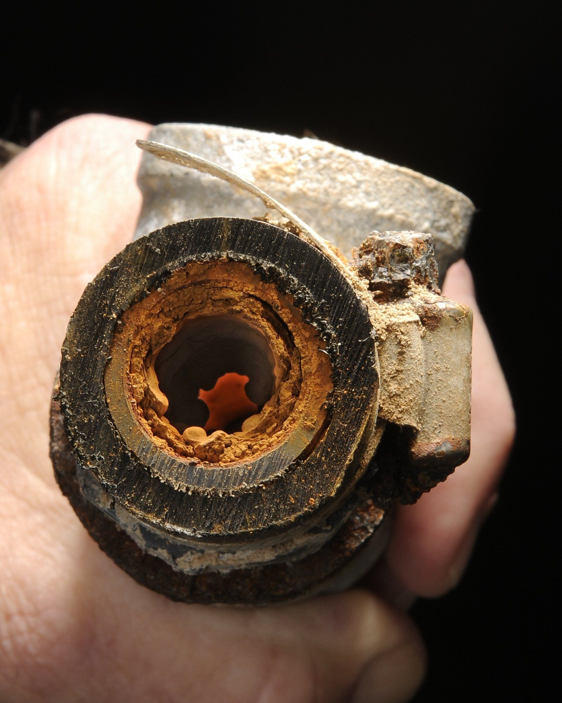 A person is holding a rusty pipe in their hand