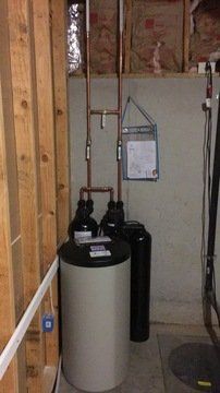 A water heater is sitting in a room next to a wall.