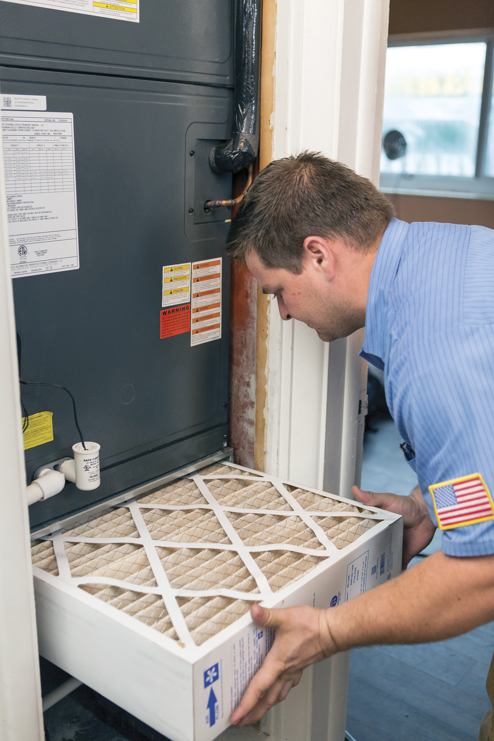 A man is changing a filter on an air conditioner.